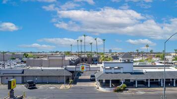 A parking lot with multiple parking spaces, a clear sky, and a few palm trees.