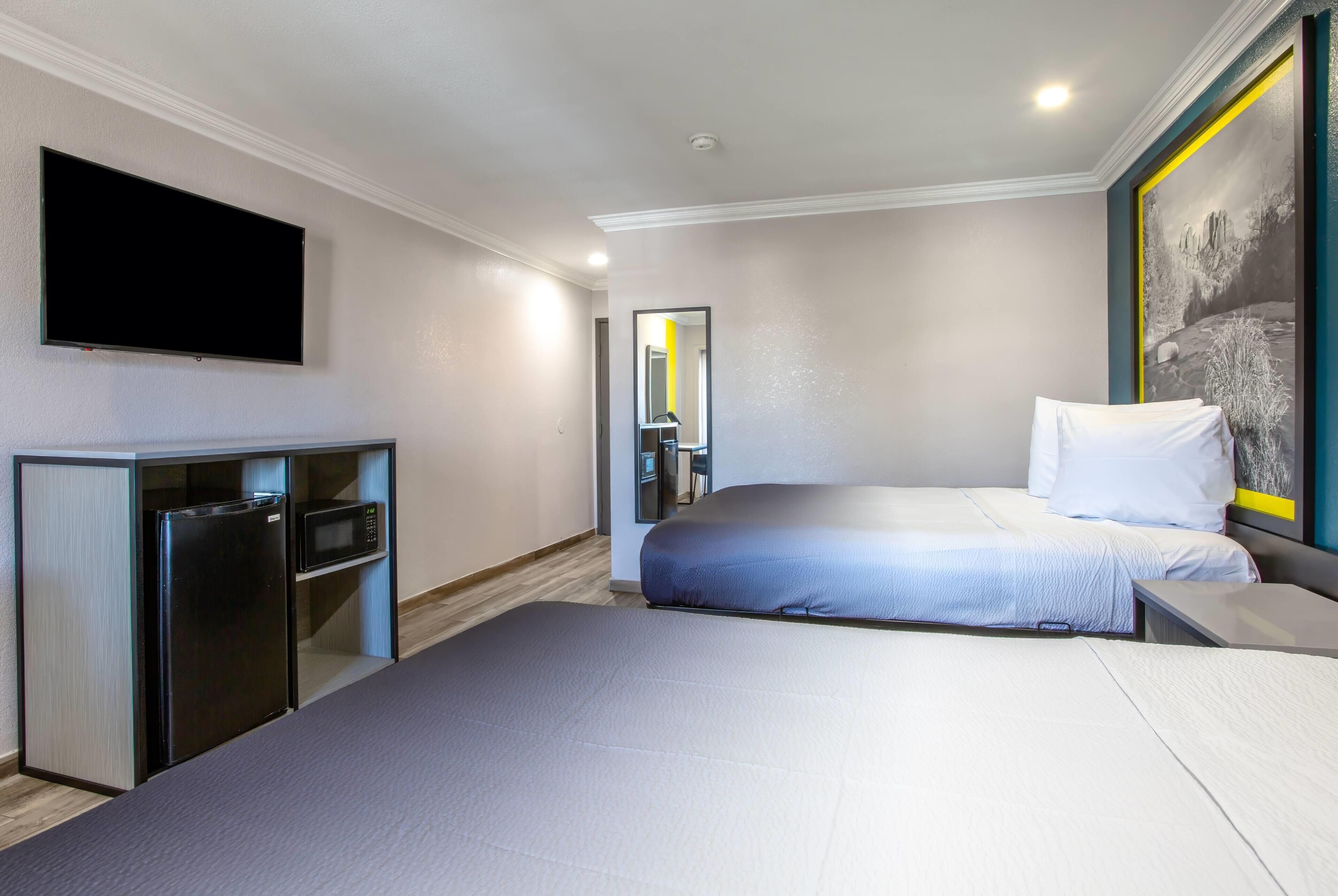 Een hotelkamer met een bed, een aan de muur bevestigde televisie, een bureau en een magnetron.