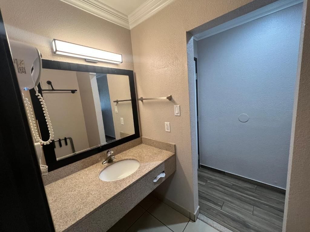 A bathroom with a sink, mirror, towel rack, and a door leading to a shower area.