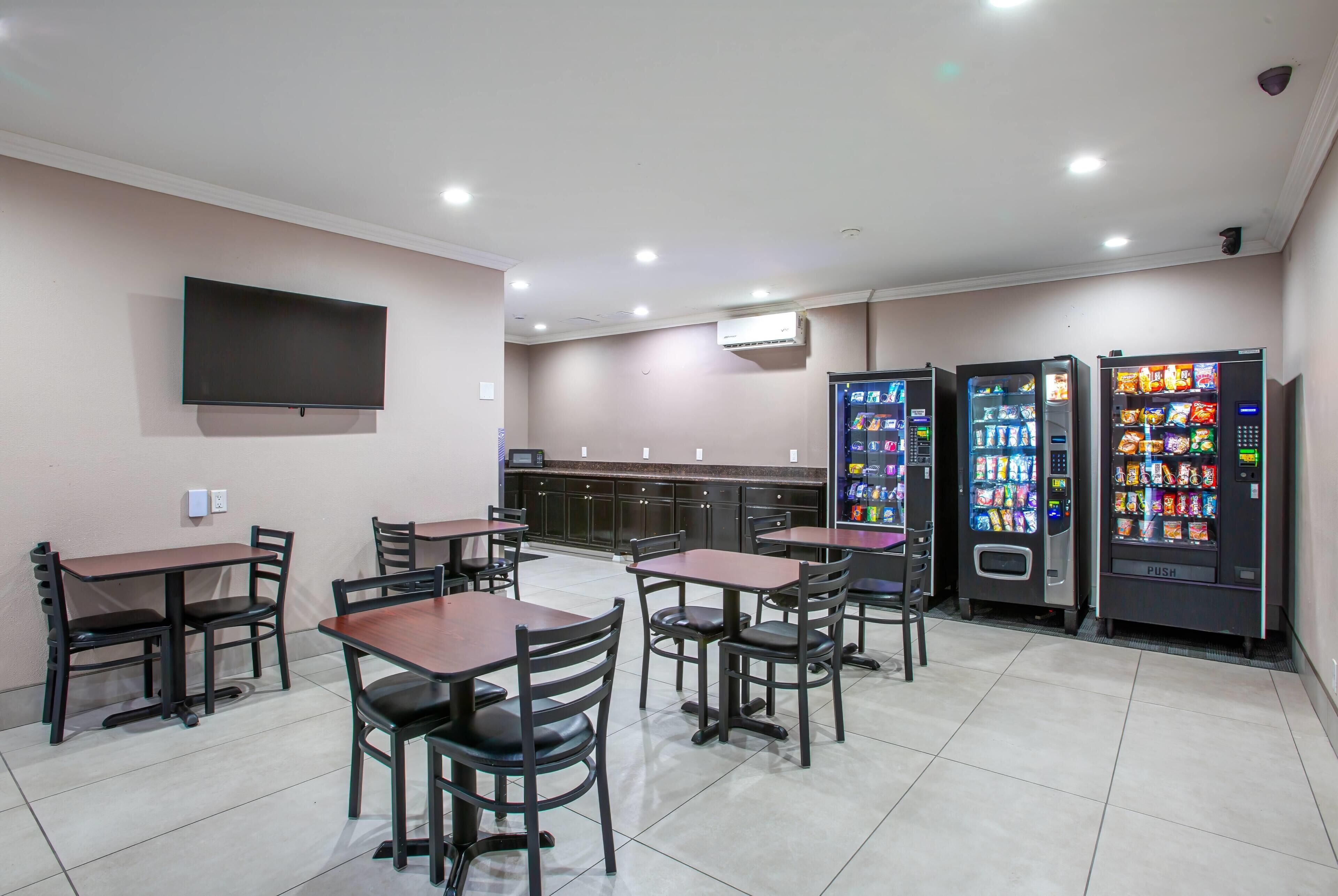 Een restaurant met tafels, stoelen, een flatscreen televisie en automaten.