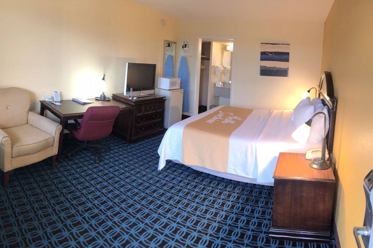 Una habitación de hotel con cama, escritorio, silla y televisor.
