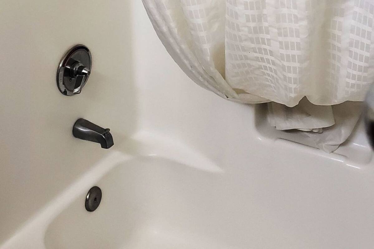 Una bañera blanca con cortina de ducha, grifo y desagüe.