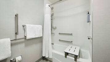 Une salle de bain moderne dotée d’une douche à l’italienne, de barres d’appui, d’un porte-serviettes et d’un support à papier toilette.