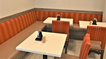 Un restaurante con asientos tipo cabina y mesas individuales, equipado con máquinas de café.