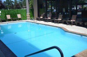 Relax by the pool surrounded by lush greenery and comfortable lounge chairs.