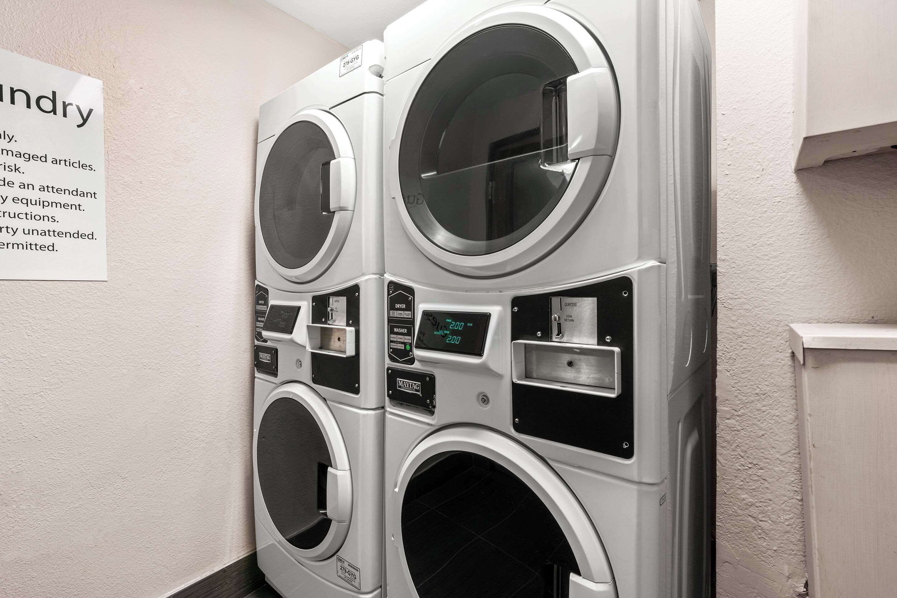 A row of stacked front-loading washing machines in a laundry room.