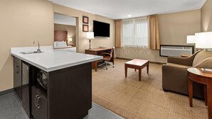 A hotel room with a kitchenette, a desk, a sofa, a TV, and a large window with curtains. - Comfort Inn & Suites Beaverton - Portland West (Beaverton)