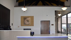 A reception desk with a digital screen, a wooden wall art piece, and a door. - Comfort Inn & Suites Beaverton - Portland West (Beaverton)