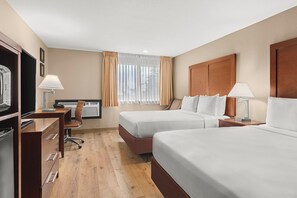 Habitación de hotel con dos camas, un escritorio con silla, televisor y ventana con cortinas.