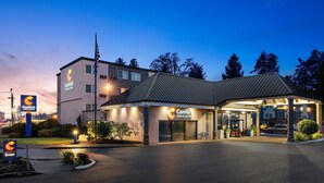 A Comfort Inn & Suites hotel with a covered outdoor area, a flagpole, and a well-lit entrance. - Comfort Inn & Suites Beaverton - Portland West (Beaverton)