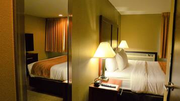A hotel room with a bed, two bedside lamps, a nightstand, a remote control, and a television on a stand.