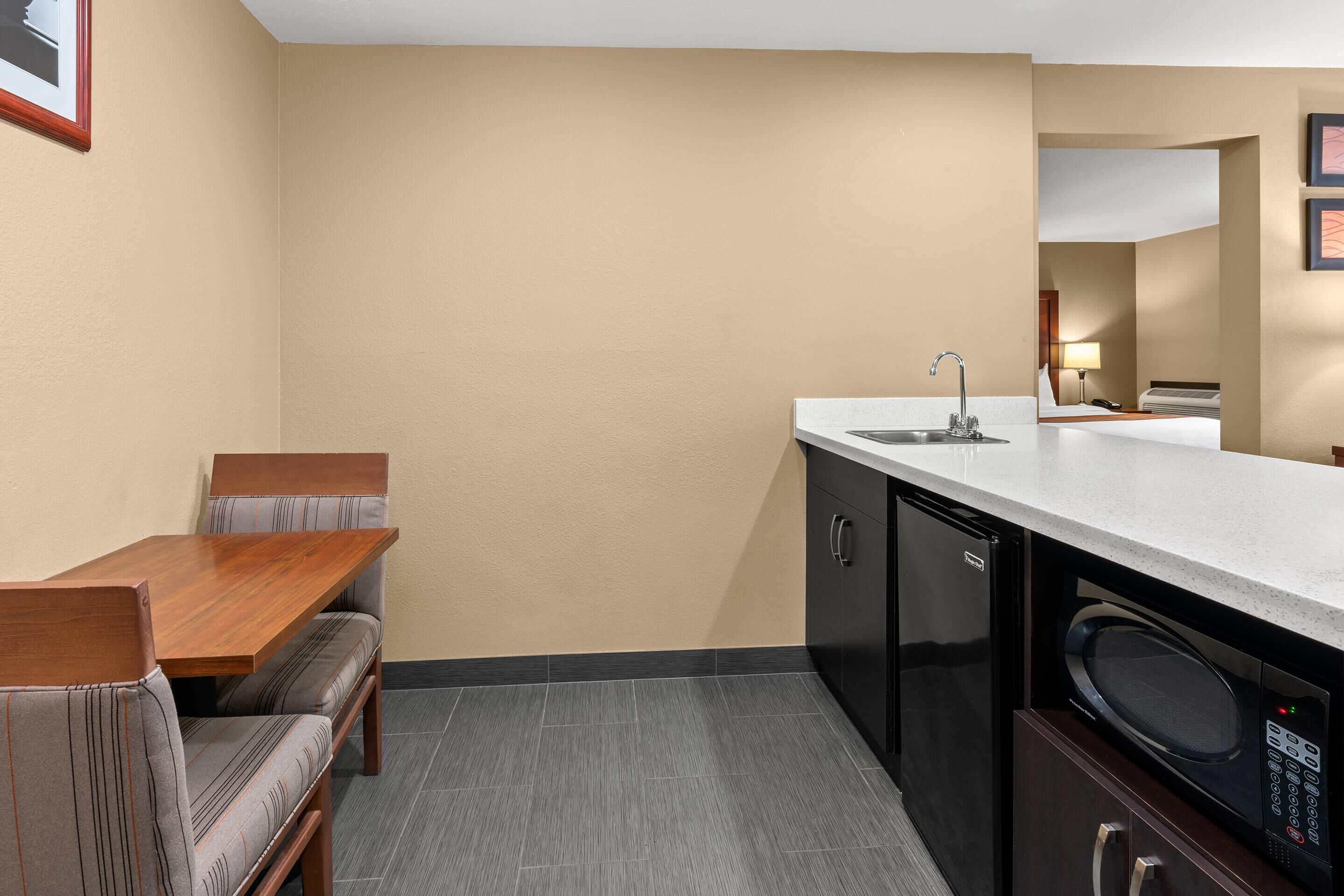 A compact kitchen with a dining table, bench seating, a microwave, and a sink.