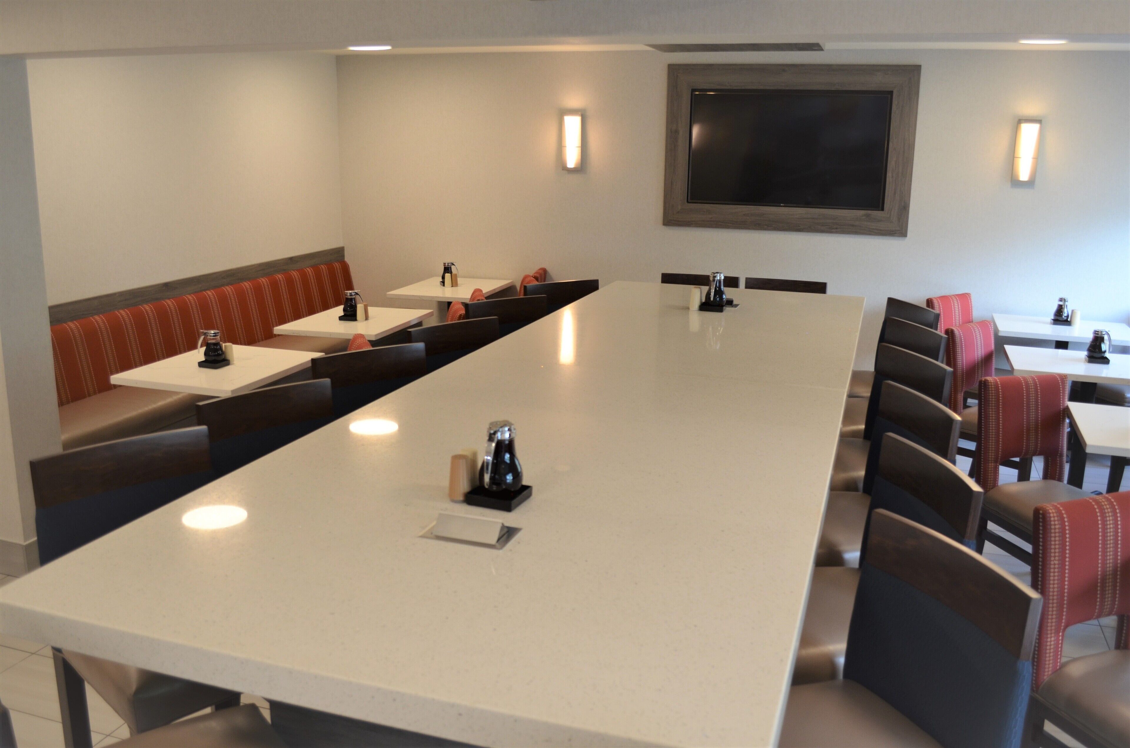 Una sala de conferencias con una mesa larga, sillas y un área de estar con bancos.