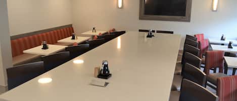 A conference room with a long table, chairs, and a seating area with benches.