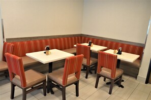 Cozy seating area with four tables and comfortable chairs, surrounded by a low bench.