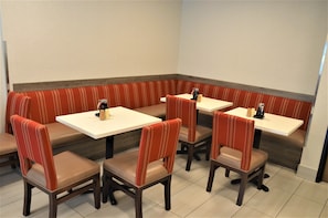 Cozy seating area with four tables and comfortable chairs, surrounded by a low bench.