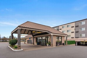 Stunning hotel entrance with a flat roof and beautiful gardens.