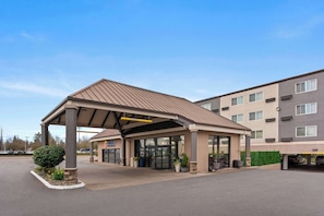 Stunning hotel entrance with a flat roof and beautiful gardens.