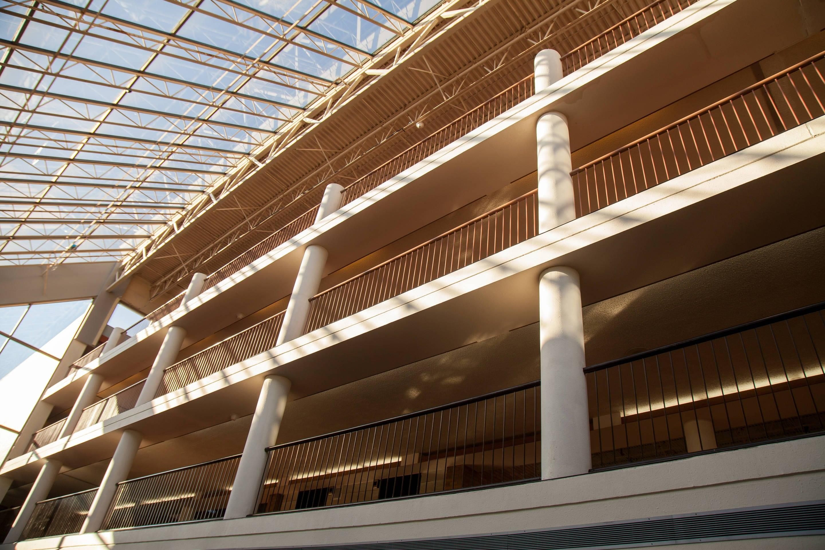 A multi-level building with a glass ceiling and white structural columns.