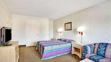 A hotel room with a bed, a sofa, a TV, and two bedside lamps.