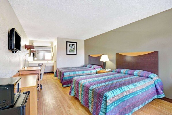 Una habitación de hotel con dos camas, un escritorio, un televisor y un microondas.