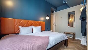Una habitación de hotel moderna con una cama grande, un banco de madera y un perchero.