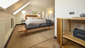 A modern hotel room with a loft bed, a bench, a wooden side table, and a Marshall speaker. - Hotel Mayfair (Copenhagen)