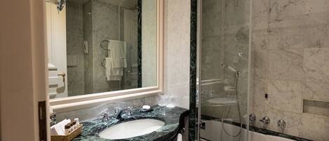 Une salle de bain avec un lavabo en marbre, une douche à parois de verre et un grand miroir.