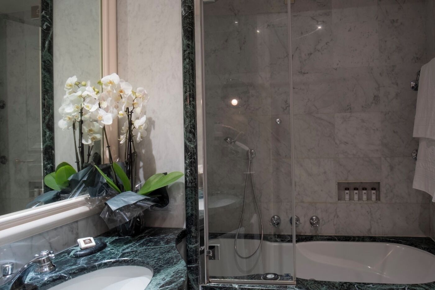 Une salle de bain moderne avec une douche à parois de verre, un lavabo en marbre et une grande baignoire.