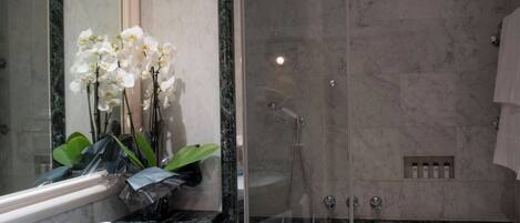 Une salle de bain moderne avec une douche à parois de verre, un lavabo en marbre et une grande baignoire.
