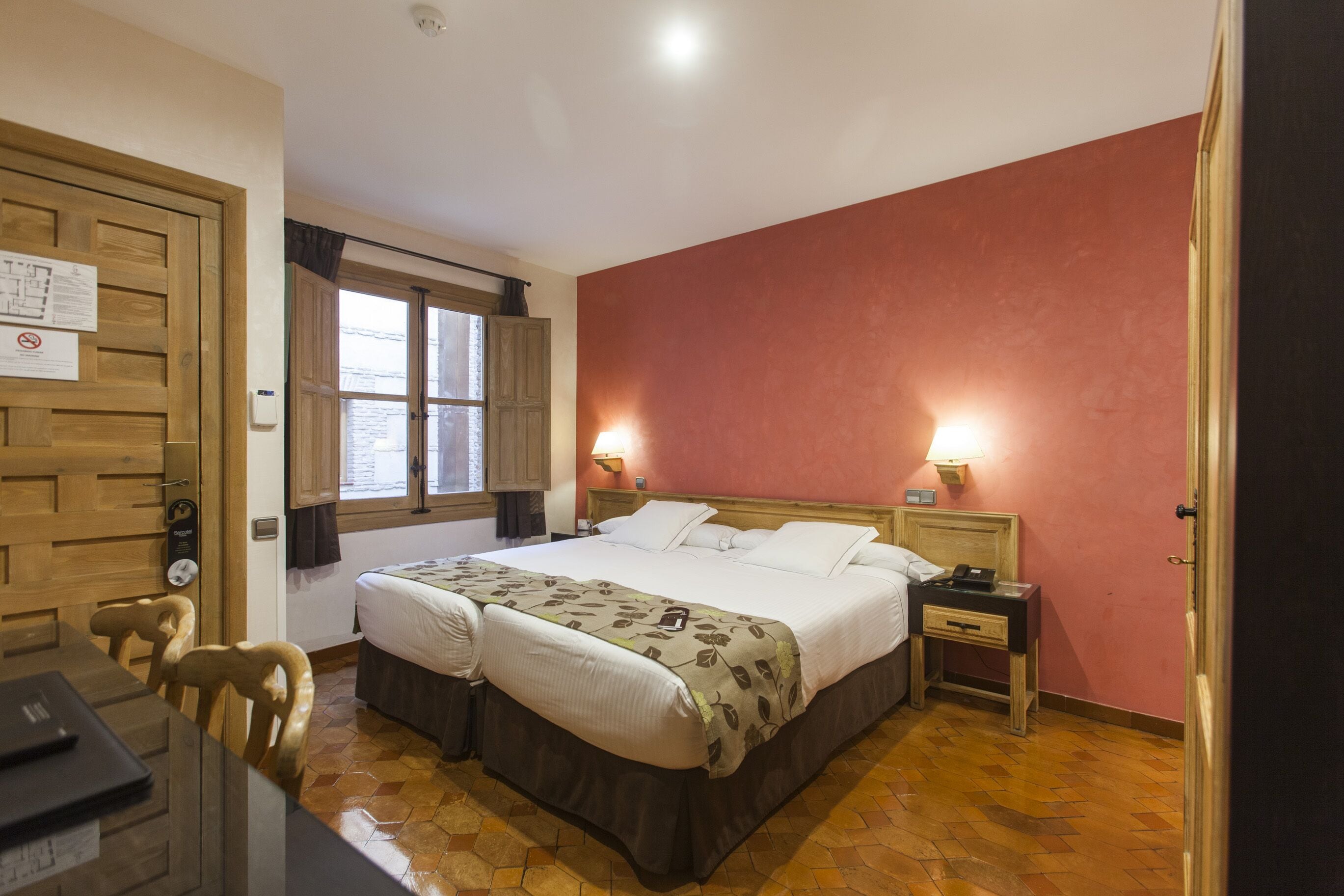 A hotel room with a bed, bedside tables, a desk, and a chair.