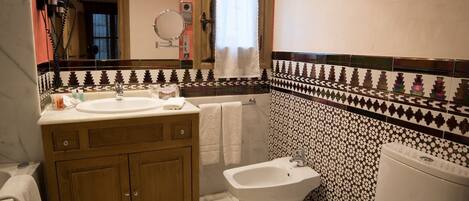 Un baño con tocador de madera, un bidé y un inodoro.