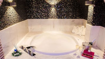 Un baño lujoso con una bañera de mármol, una botella de champán y un par de zapatos blancos.
