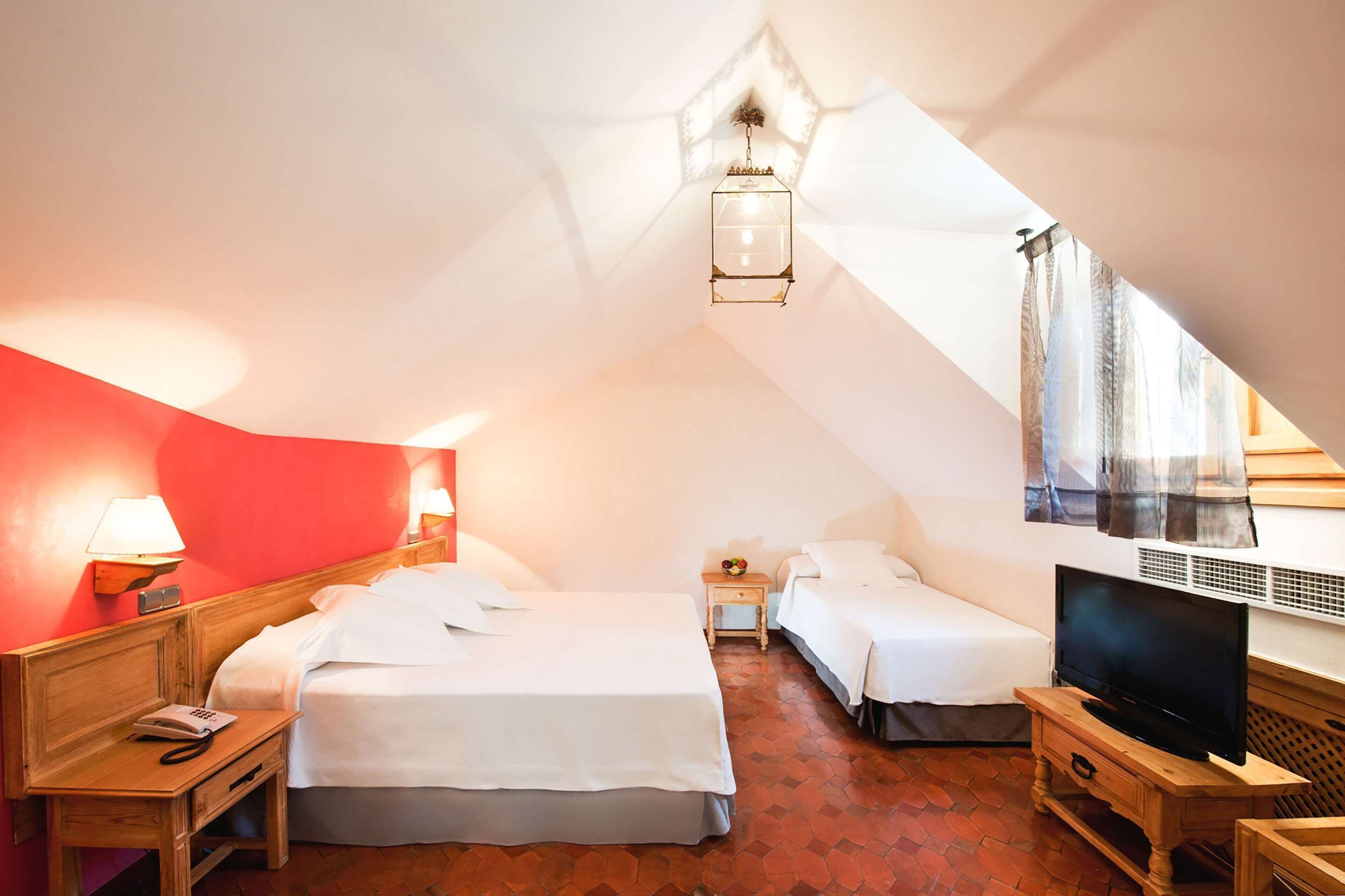 Een gezellige, driehoekige kamer met een bed, een televisie en een kleine tafel.