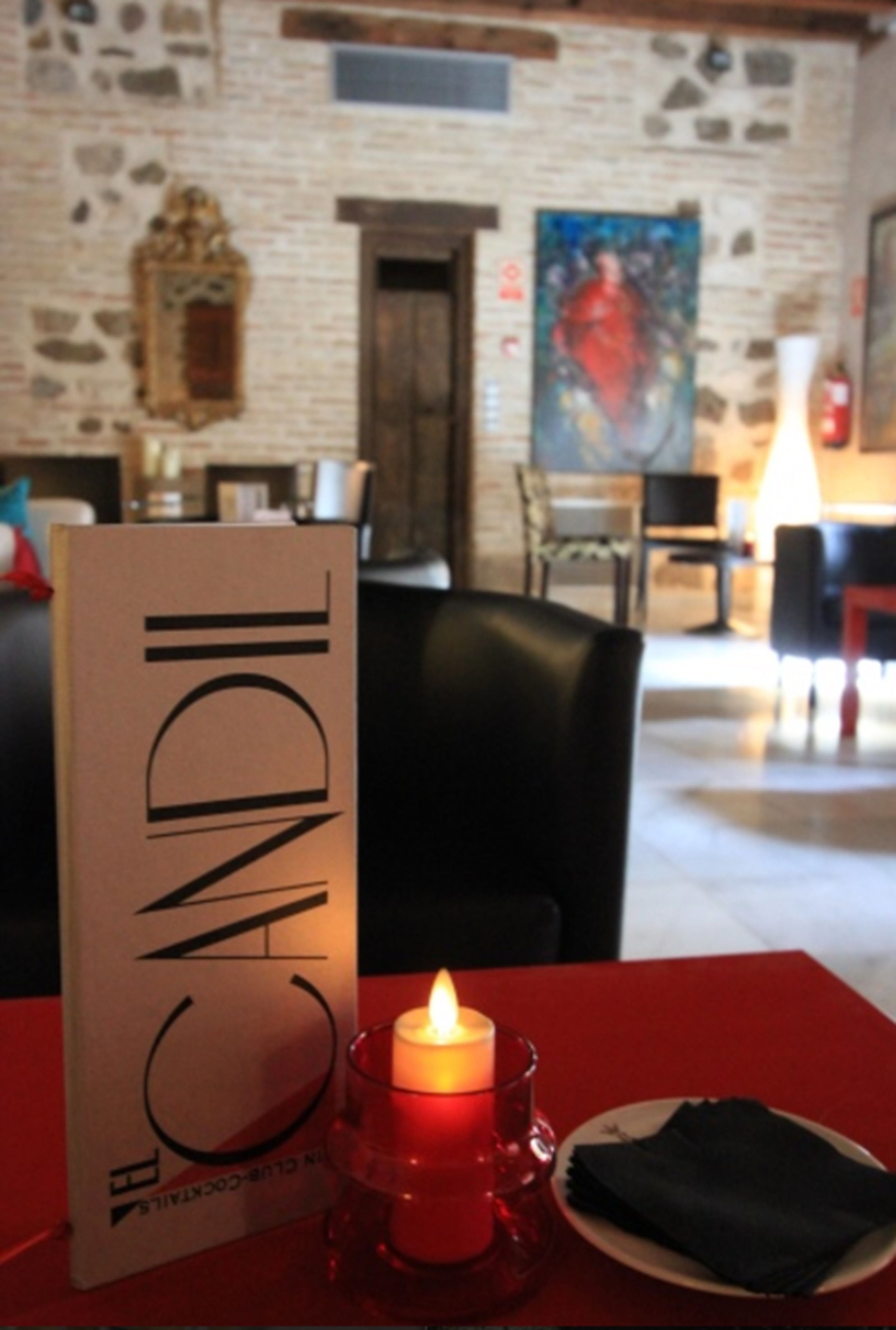 A candle on a table with a menu stand labeled "CANDLE" in a restaurant setting.