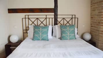 A bed with a wooden headboard, white bedding, and teal pillows.