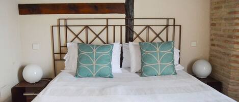 A bed with a wooden headboard, white bedding, and teal pillows.