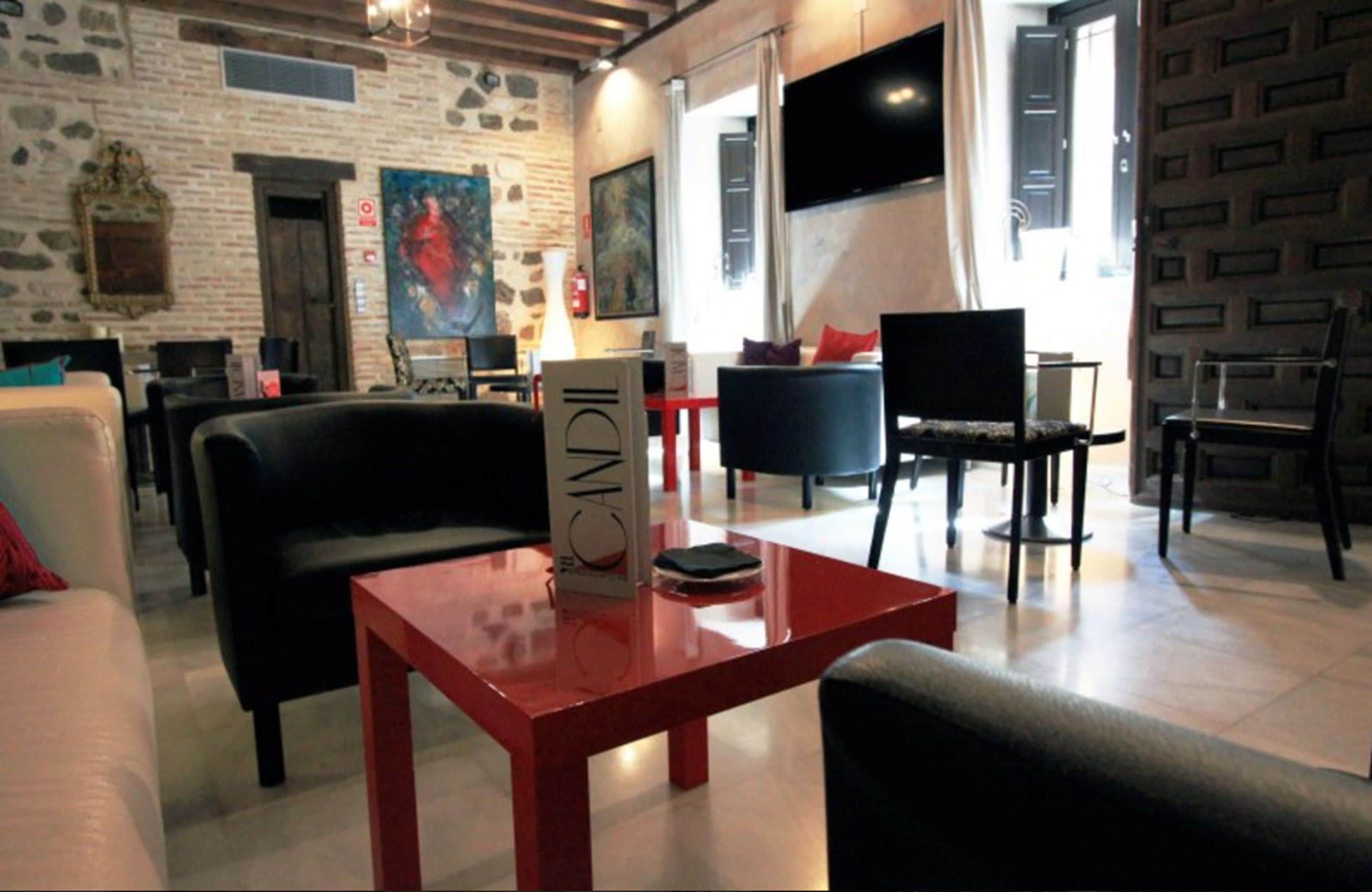 Un área de estar moderna con pared de piedra, una mesa roja y mobiliario blanco y negro.
