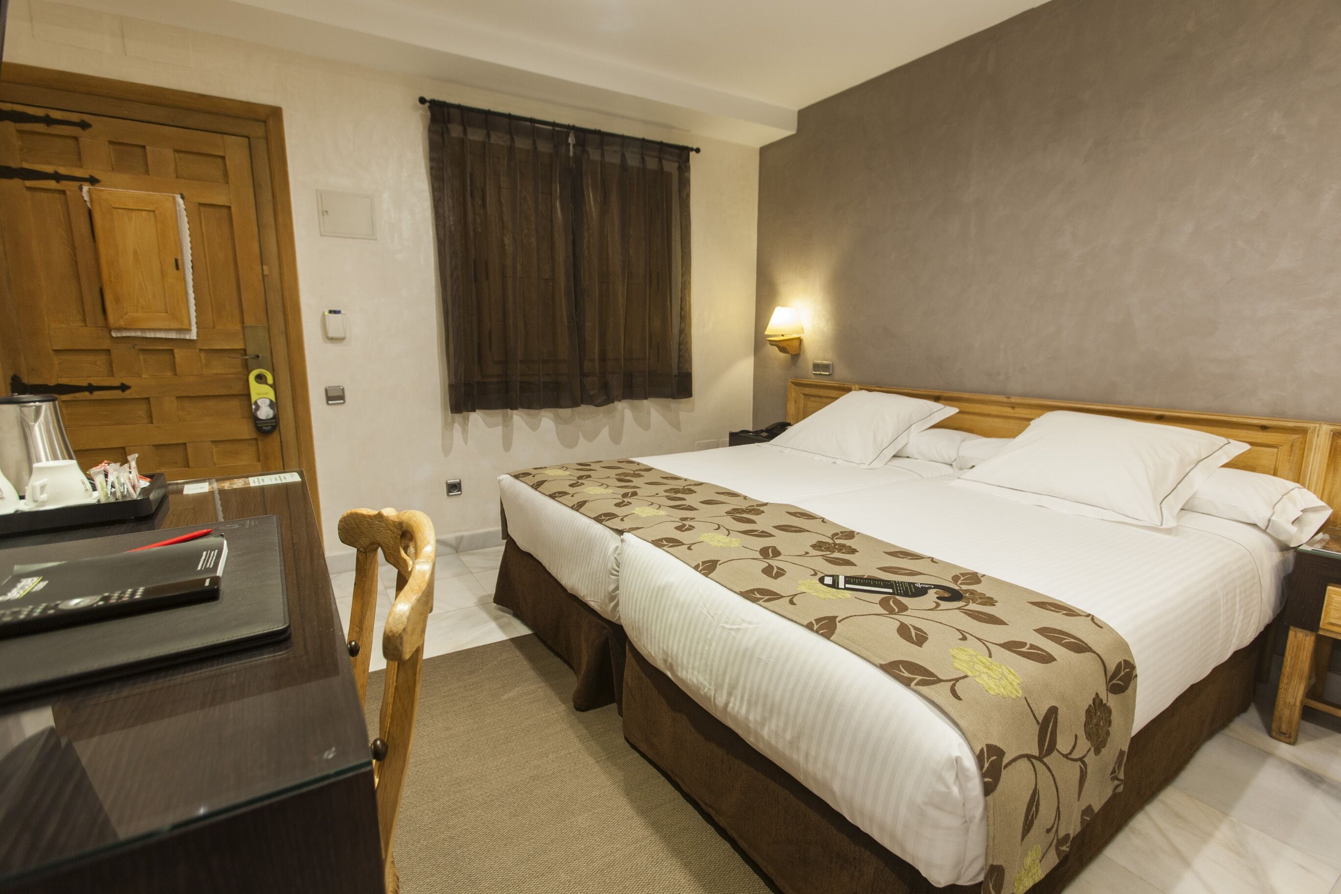 Een hotelkamer met een groot bed, een bureau met een laptop, een stoel en een houten deur.