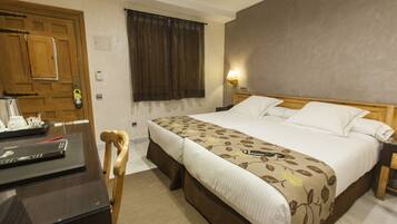 Een hotelkamer met een groot bed, een bureau met een laptop, een stoel en een houten deur.