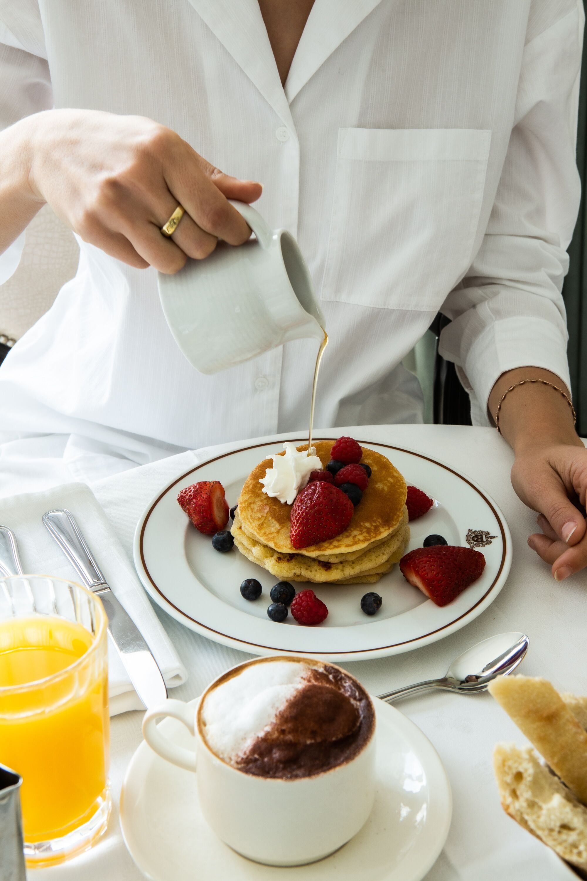 A breakfast setting with pancakes, strawberries, blueberries, and a cup of coffee.