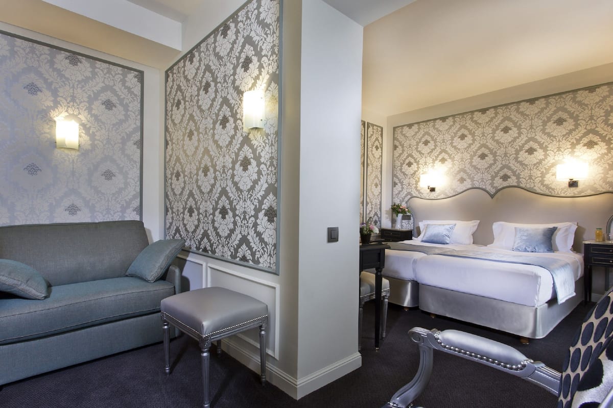 Una habitación de hotel con sofá, cama, silla y mesita de noche.