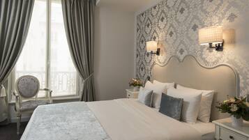 A hotel room with a large bed, two bedside lamps, a chair, and a window with curtains.