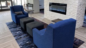 A modern lounge area with a stone accent wall, a flat-screen TV, and a fireplace. - Comfort Inn Chicago Schaumburg - O'Hare Airport (Schaumburg)