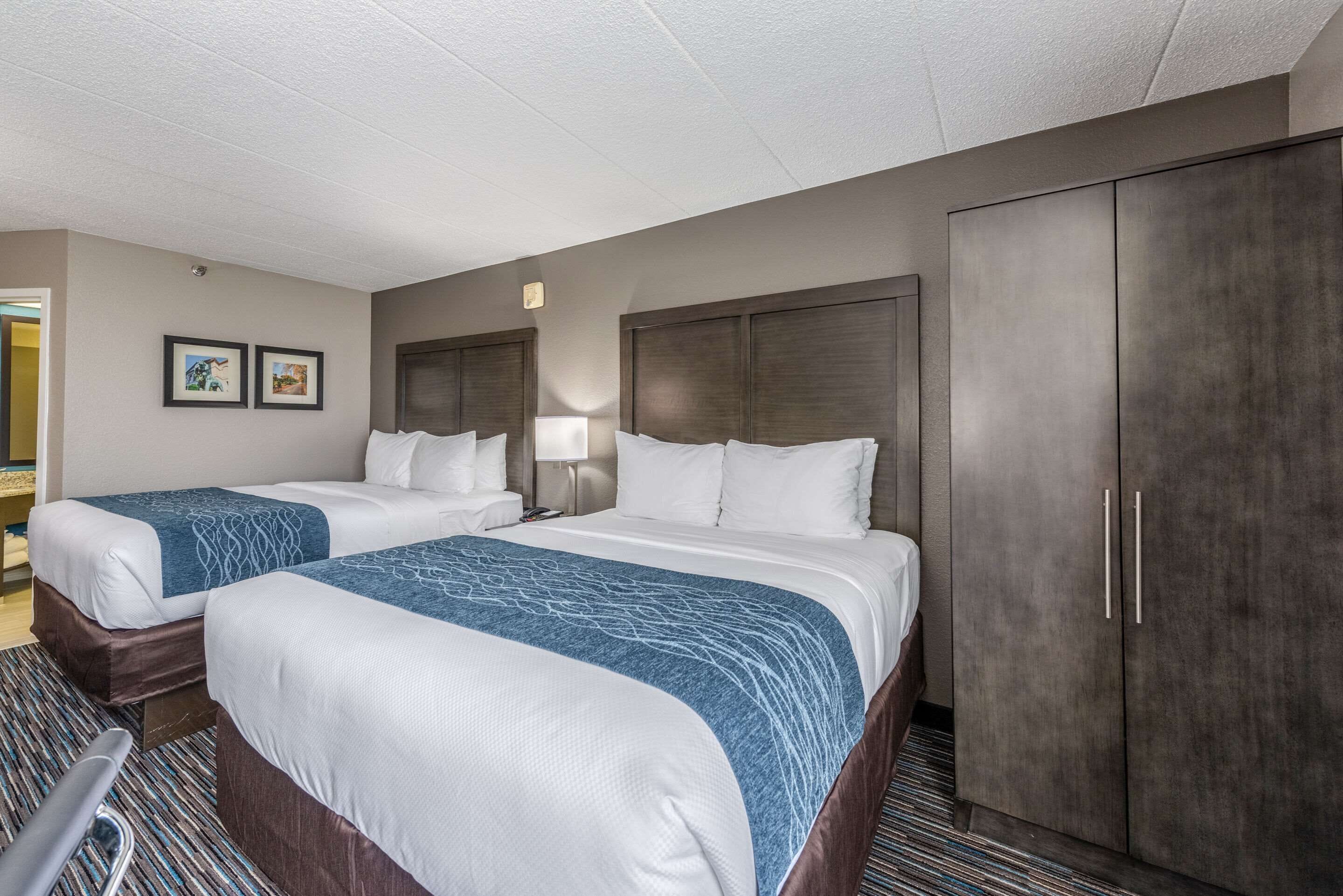 A hotel room with two beds, a wardrobe, a desk, and a chair.