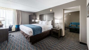 A hotel room with a large bed, bedside tables, a desk, and a seating area with a sofa. - Comfort Inn Chicago Schaumburg - O'Hare Airport (Schaumburg)