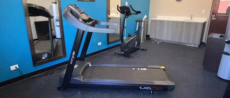 A fitness room with treadmills, a mirror, and a clock on the wall.