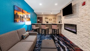 A modern hotel lobby with a blue accent wall, a bar area, a fireplace, and a sofa with a patterned pillow. - Comfort Inn Chicago Schaumburg - O'Hare Airport (Schaumburg)
