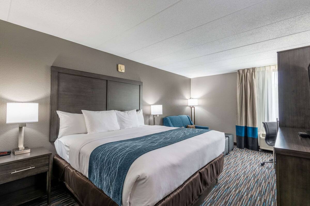 Een hotelkamer met een bed, bedlampen, een bureau en een stoel.