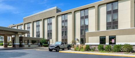 A modern building with a parking lot and a parked vehicle.